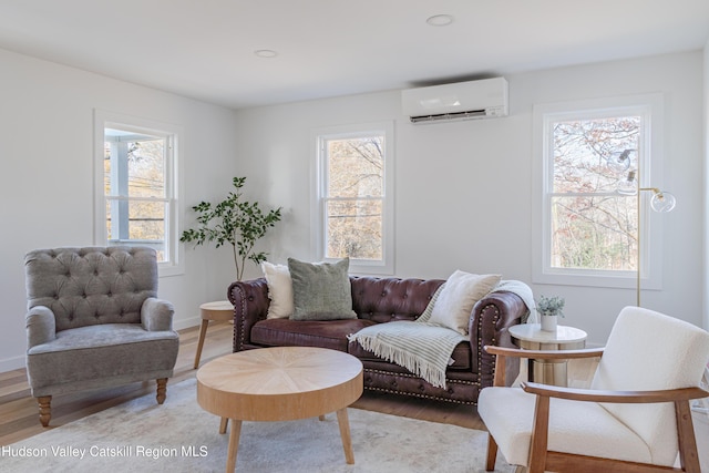 living room with an AC wall unit, plenty of natural light, and light hardwood / wood-style flooring