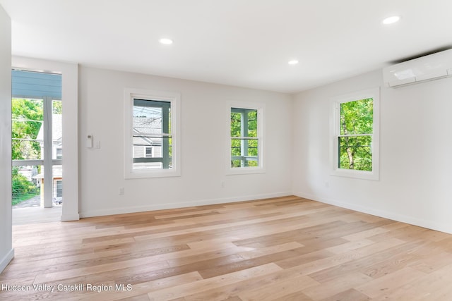 spare room with an AC wall unit and light hardwood / wood-style flooring