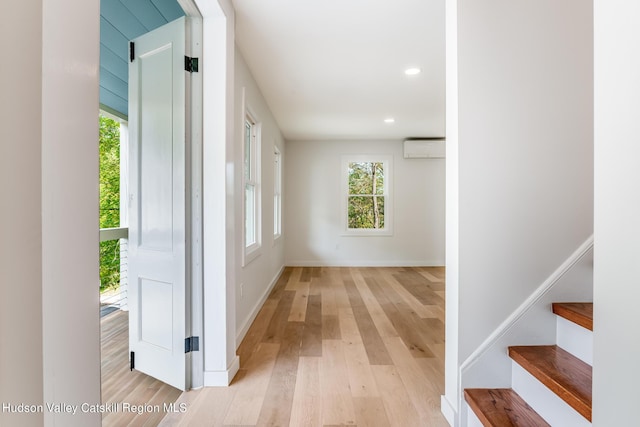 hallway featuring light hardwood / wood-style flooring and a wall mounted AC