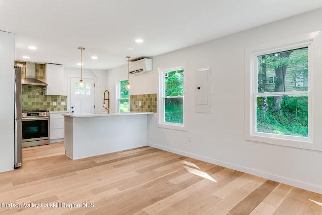 kitchen featuring backsplash, white cabinets, stainless steel stove, kitchen peninsula, and a wall unit AC