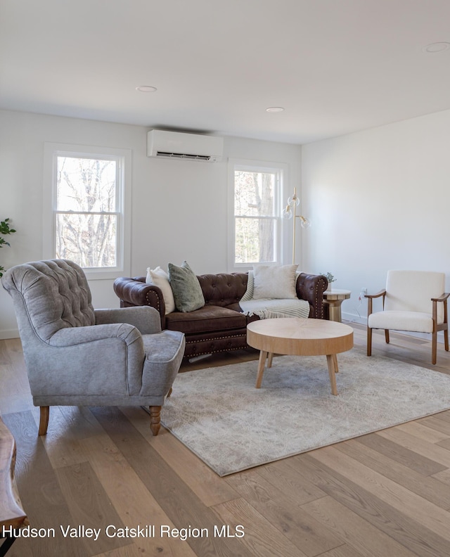 living room with a wall mounted air conditioner and hardwood / wood-style flooring