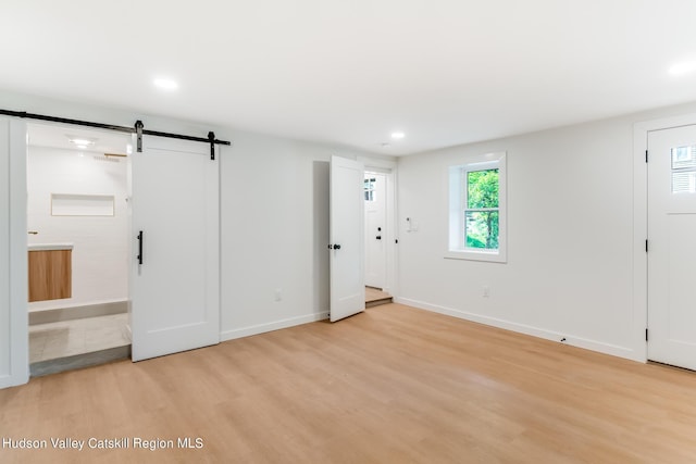 interior space with a barn door, light wood-type flooring, and connected bathroom