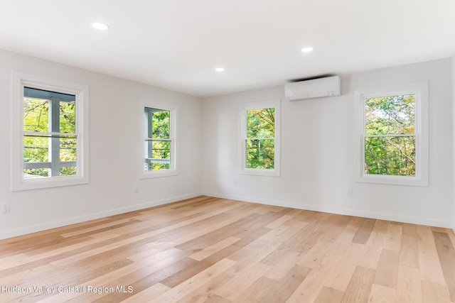 empty room featuring an AC wall unit and light wood-type flooring