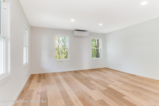 spare room featuring light hardwood / wood-style flooring and a wall mounted air conditioner