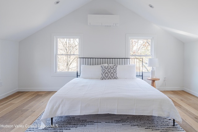 bedroom with lofted ceiling, light wood-type flooring, multiple windows, and a wall mounted AC