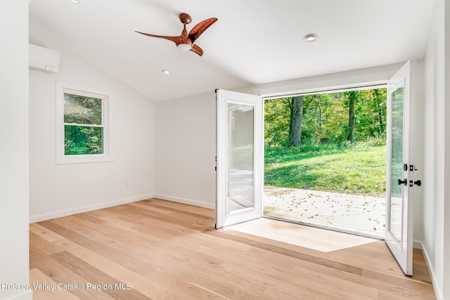 entryway featuring vaulted ceiling, light hardwood / wood-style flooring, an AC wall unit, and a wealth of natural light