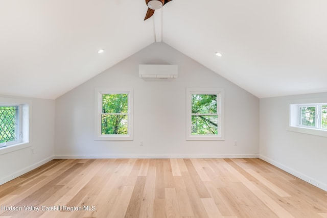 additional living space with a wall mounted AC, a wealth of natural light, and light wood-type flooring