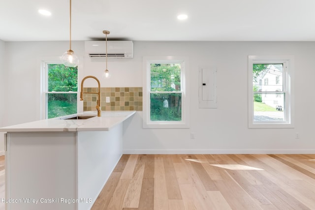 kitchen featuring sink, hanging light fixtures, a wall mounted air conditioner, kitchen peninsula, and electric panel