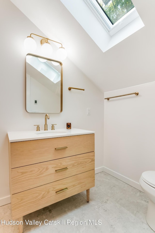 bathroom with vanity, toilet, and lofted ceiling with skylight