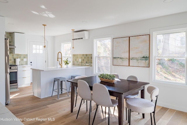 dining area with light hardwood / wood-style floors, sink, and a wall unit AC