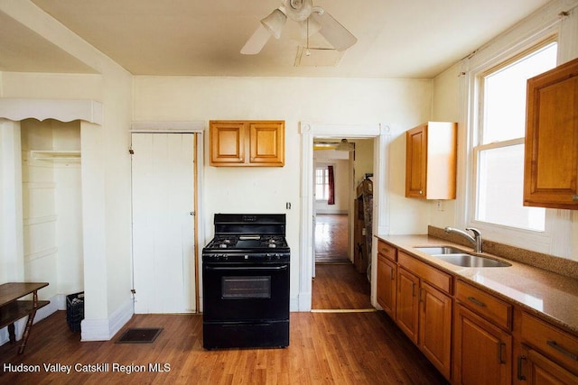 604 Columbia St, Hudson, NY 12534 - kitchen with black gas range oven, a sink, wood finished floors, and brown cabinets