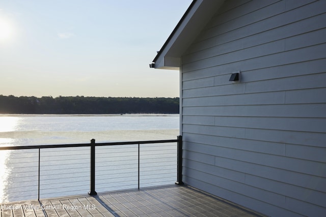 balcony at dusk featuring a water view