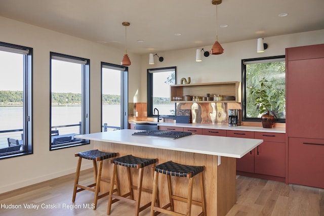 kitchen featuring a center island, stainless steel gas stovetop, a breakfast bar, sink, and light hardwood / wood-style flooring