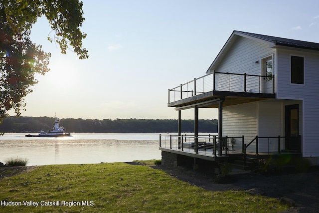 view of dock with a yard and a water view