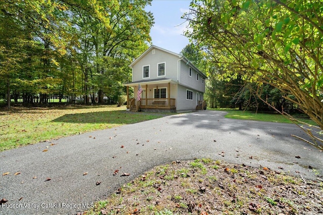 view of front of home with a porch, aphalt driveway, and a front yard