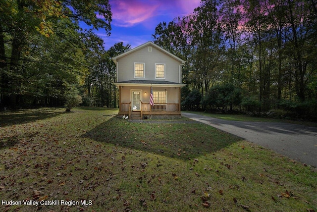 view of front of property with covered porch and a yard