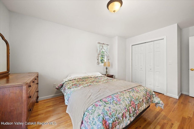 bedroom featuring baseboards, light wood finished floors, and a closet