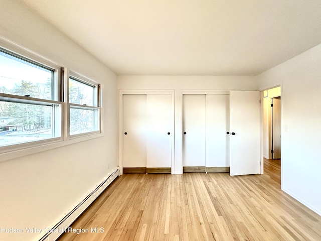 32 Redwood Rd, Saugerties, NY 12477 - unfurnished bedroom with multiple closets, a baseboard radiator, and light wood-style flooring