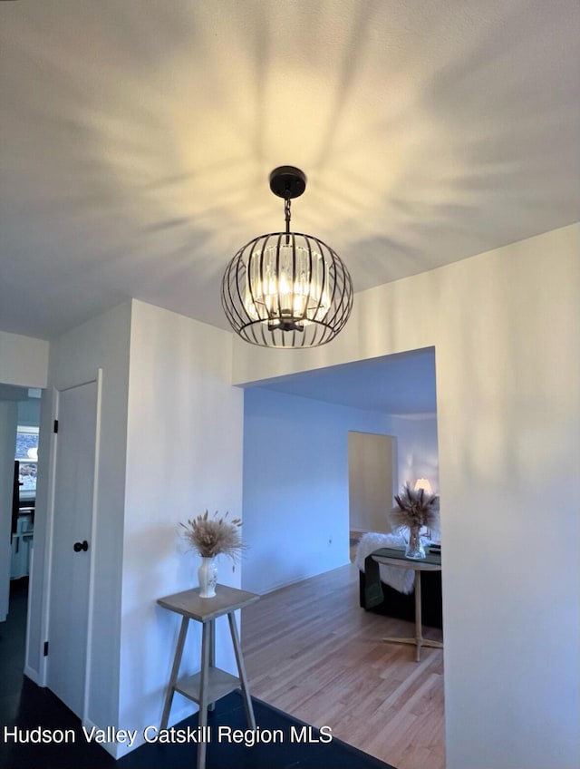 corridor featuring wood-type flooring and an inviting chandelier