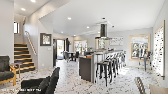 kitchen featuring a kitchen bar, kitchen peninsula, and island exhaust hood