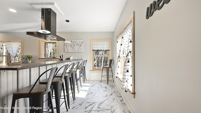 kitchen with island range hood, a breakfast bar area, and kitchen peninsula