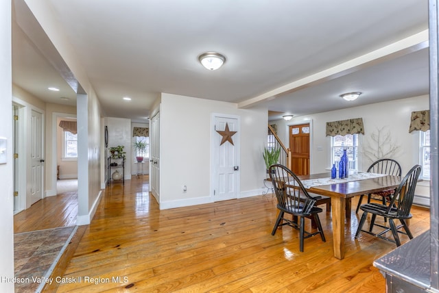 dining area with baseboards, stairway, and light wood finished floors