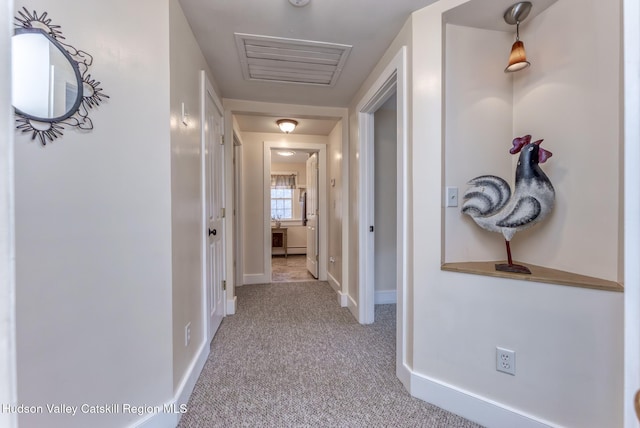 hall with carpet flooring, visible vents, and baseboards