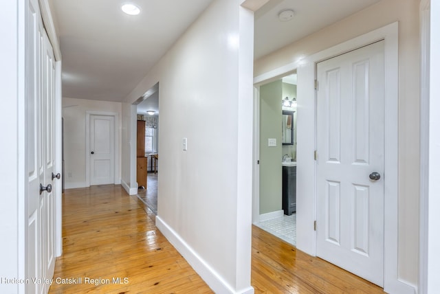 corridor with light wood-style flooring and baseboards