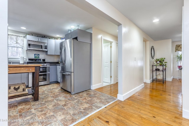 kitchen featuring stainless steel appliances, light wood-type flooring, baseboards, and recessed lighting