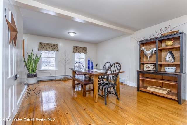 dining room featuring light wood-style flooring, a baseboard heating unit, and baseboards