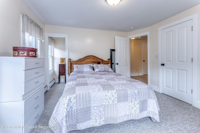 bedroom with light carpet, a baseboard heating unit, and baseboards