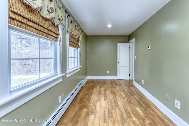 spare room featuring baseboards, baseboard heating, and wood finished floors