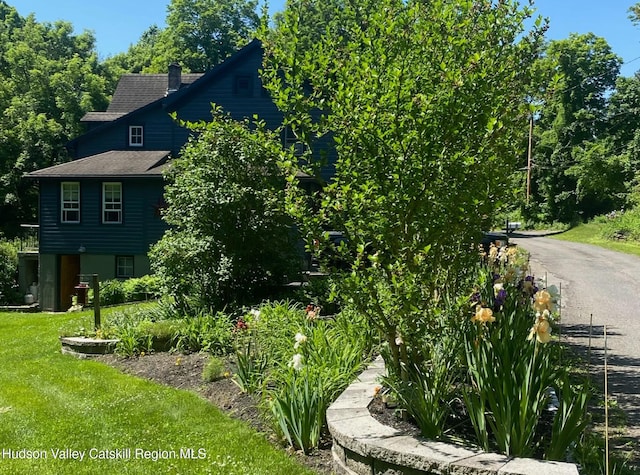 view of home's exterior with a shingled roof and a yard