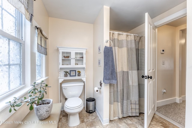 bathroom with a shower with shower curtain, toilet, and baseboards