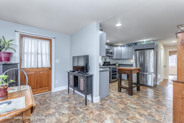 kitchen featuring stainless steel appliances, recessed lighting, stone finish floor, and baseboards