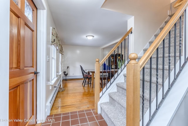 staircase featuring a baseboard radiator, a healthy amount of sunlight, and tile patterned floors