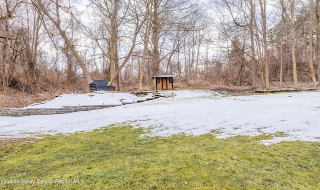 yard layered in snow featuring a storage unit and an outdoor structure