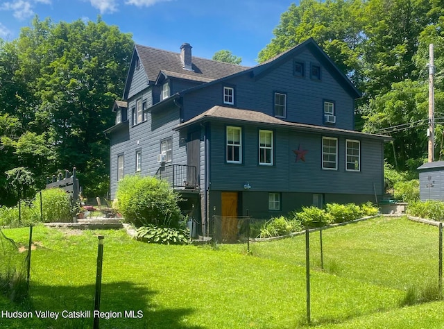 view of front of house featuring a front yard, roof with shingles, fence, and a chimney