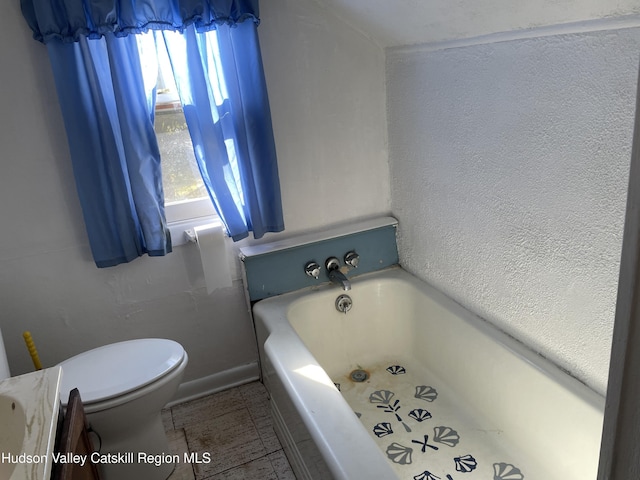 bathroom featuring a tub, a wealth of natural light, and toilet