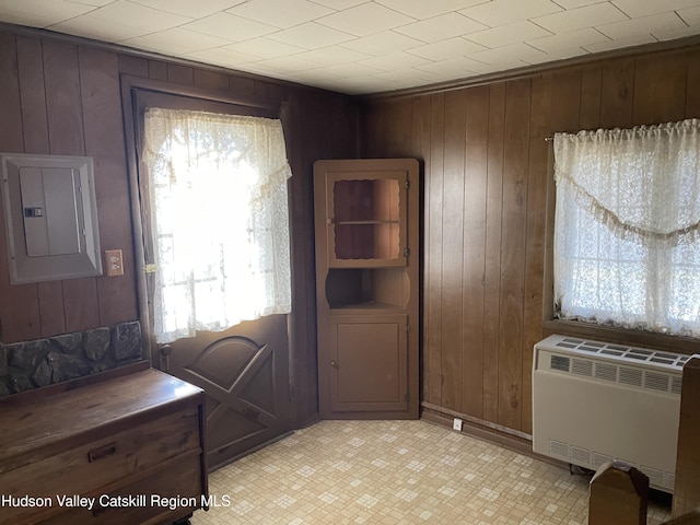 interior space with wood walls, radiator heating unit, and electric panel