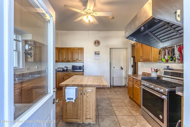 kitchen featuring sink, extractor fan, wooden counters, a center island, and appliances with stainless steel finishes