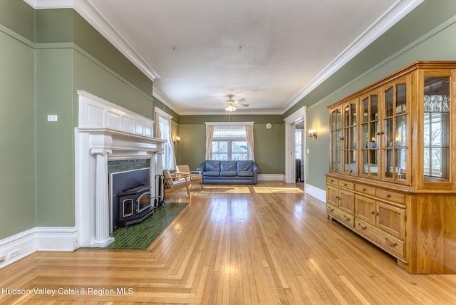 unfurnished living room featuring crown molding, a wood stove, and ceiling fan