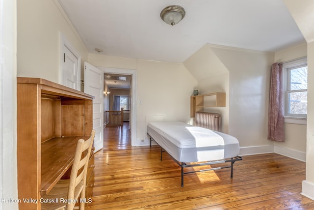 bedroom featuring hardwood / wood-style flooring, radiator heating unit, and ornamental molding