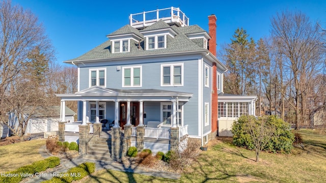 traditional style home featuring a porch, a shingled roof, and a chimney
