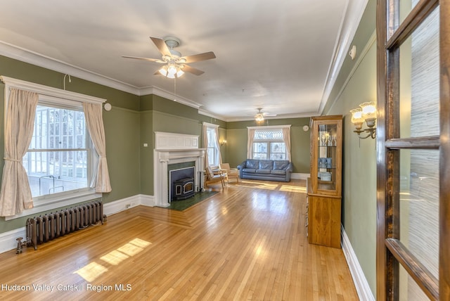 unfurnished living room with ornamental molding, a wealth of natural light, radiator, and light wood-type flooring