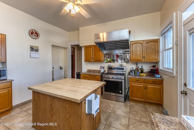 kitchen with ceiling fan, butcher block counters, stainless steel appliances, ventilation hood, and a kitchen island