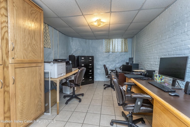 tiled office featuring a paneled ceiling and brick wall