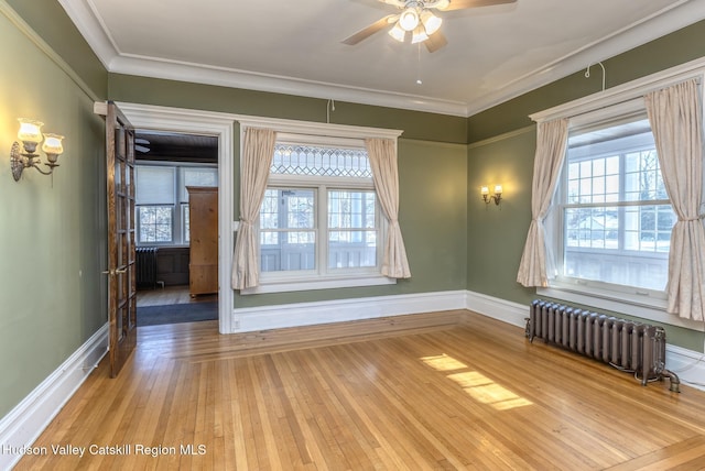 empty room featuring crown molding, radiator, hardwood / wood-style floors, and ceiling fan