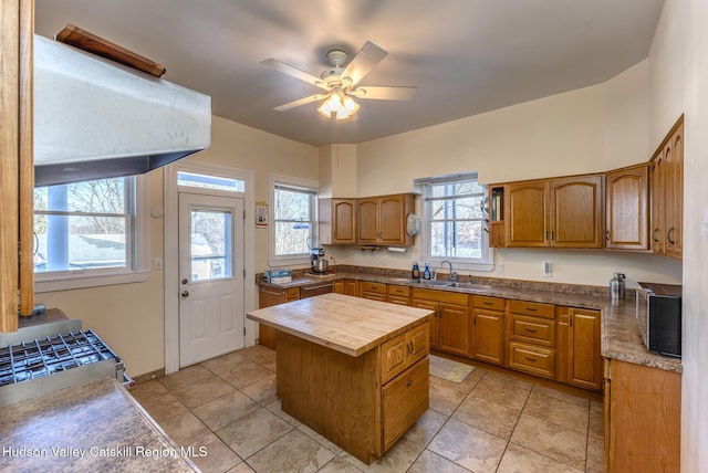 kitchen with light tile patterned flooring, ceiling fan, sink, and a kitchen island