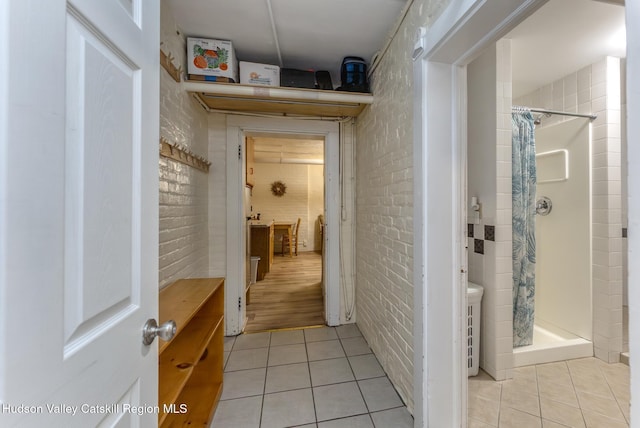 corridor with brick wall and light tile patterned floors